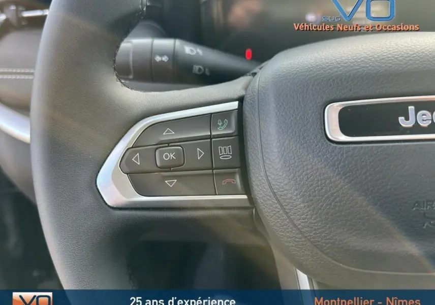 Gros plan sur le volant cuir noir du Jeep Compass 2024 avec commandes multifonctions et logo Jeep visible au centre.