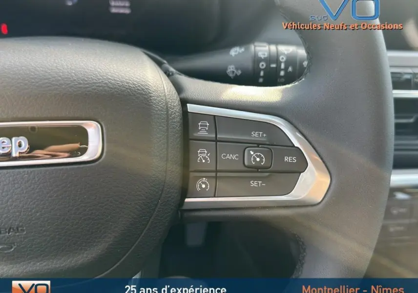 Gros plan sur le volant noir du Jeep Compass 2024 montrant les commandes du régulateur de vitesse à droite.