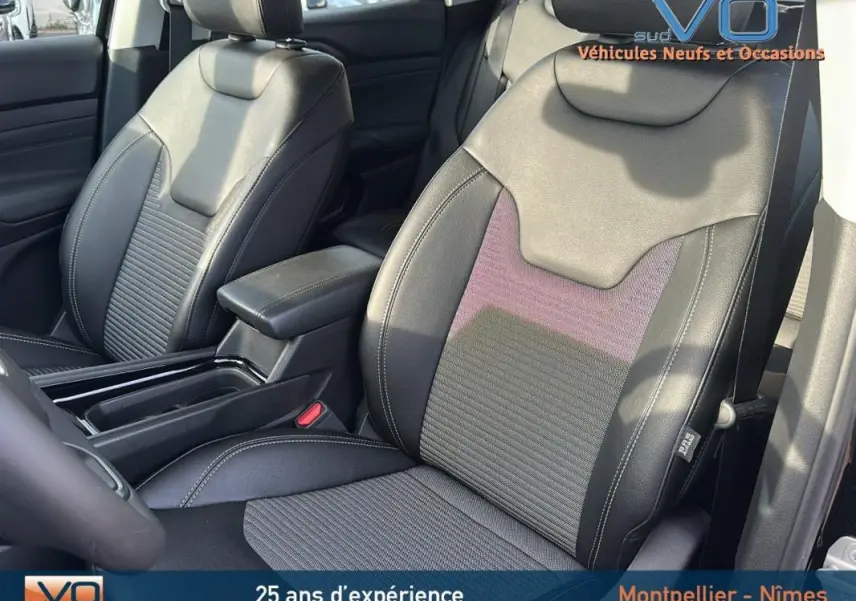 Gros plan sur les sièges avant en cuir noir du Jeep Compass 2024 avec accoudoir central et finitions soignées.