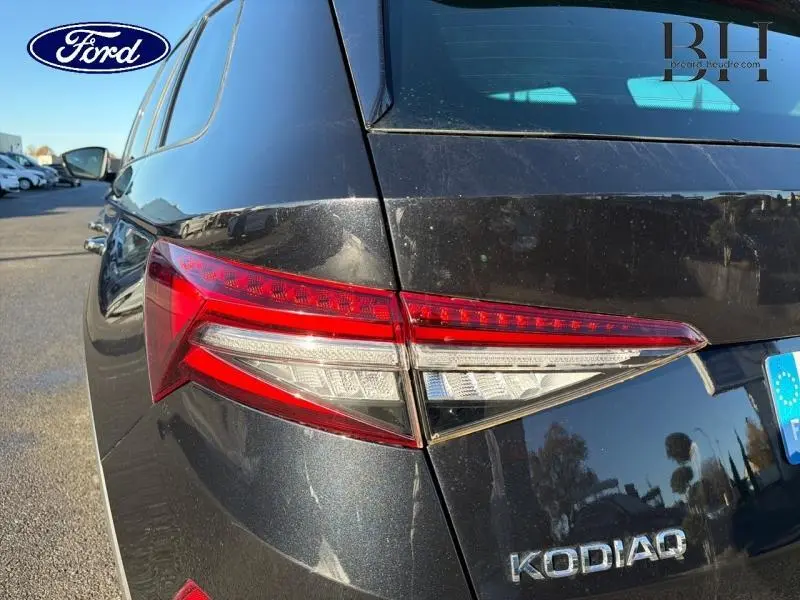 Gros plan sur le feu arrière gauche d'un SKODA KODIAQ noir Magic Nacré avec logo et plaque européenne visibles.