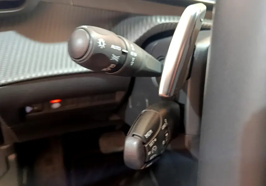 Gros plan sur les commandes de clignotants et essuie-glaces du Peugeot 2008 gris clair côté gauche du volant.