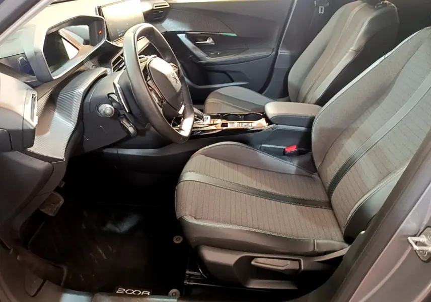 Intérieur avant droit du Peugeot 2008 gris clair 2021, sièges tissu, volant cuir et tableau de bord numérique.