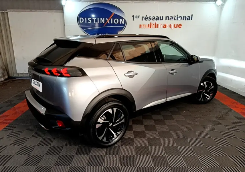 Peugeot 2008 gris clair vue 3/4 arrière droit, avec feux arrière LED et jantes noires stylisées.