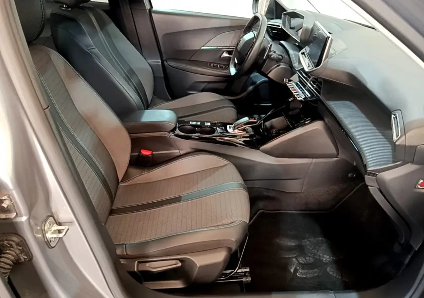 Intérieur avant droit du Peugeot 2008 gris clair 2021, sièges tissu, tableau de bord avec écran tactile et volant cuir.