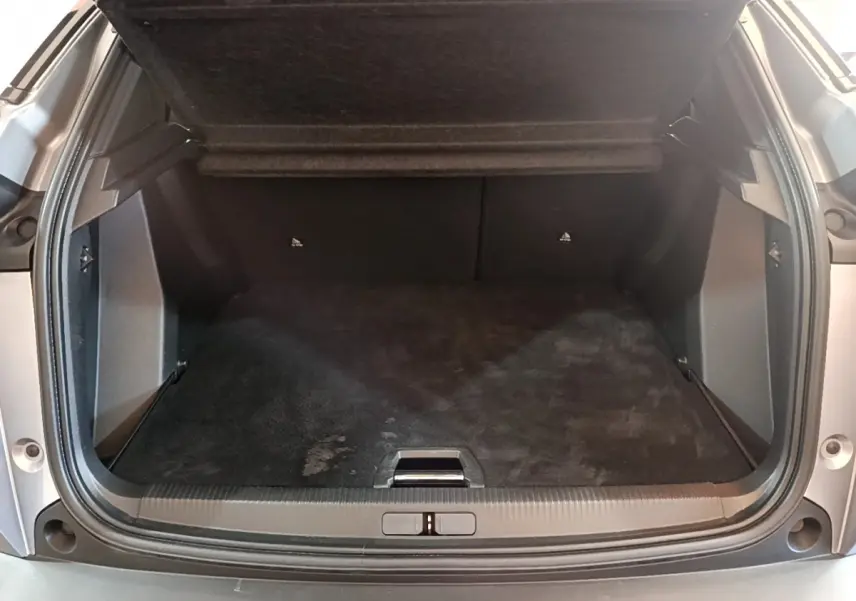 Coffre ouvert vu de l'arrière d'un Peugeot 2008 gris clair, espace de chargement propre et spacieux.