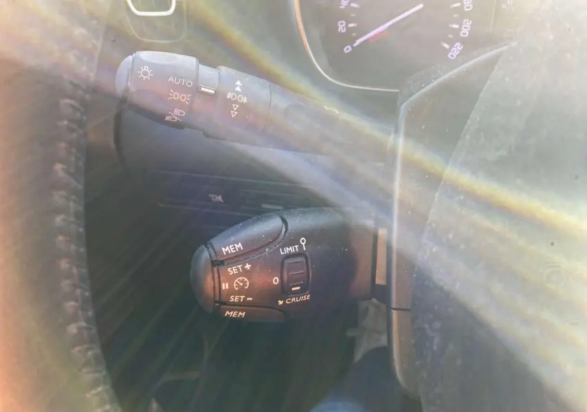 Gros plan sur les commandes au volant du Citroën C3 Aircross 2024 gris foncé, avec régulateur de vitesse et feux automatiques.