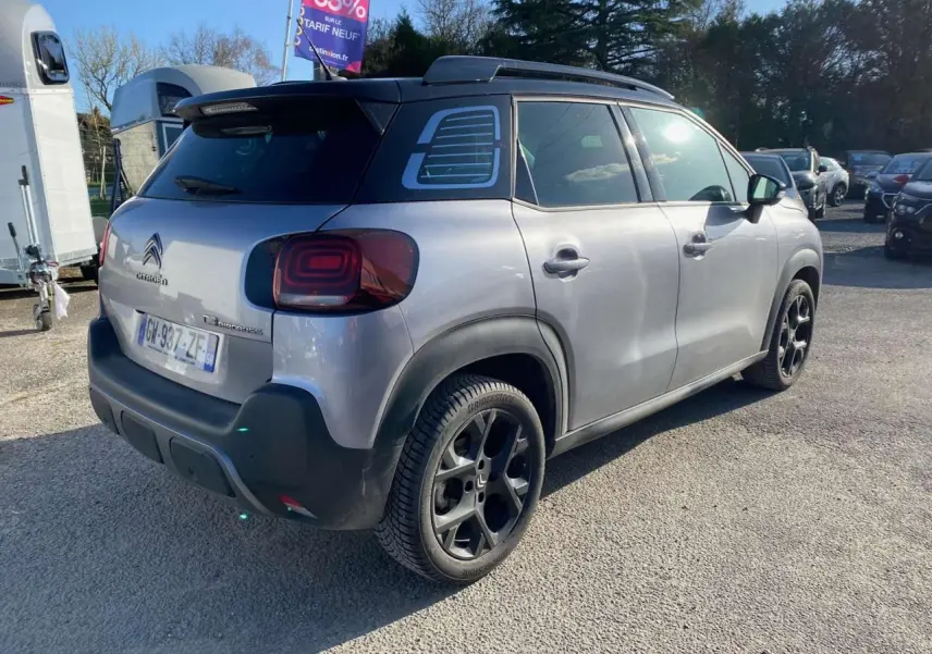 Vue 3/4 arrière droite d'un Citroën C3 Aircross gris foncé 2024 avec jantes noires et toit noir contrasté.