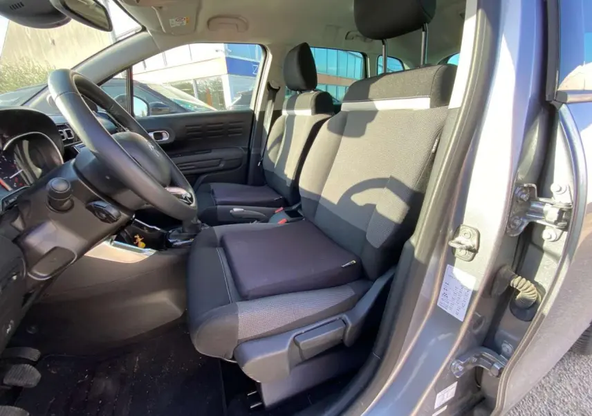 Vue intérieure côté conducteur du Citroën C3 Aircross gris foncé 2024, montrant les sièges avant et le volant.