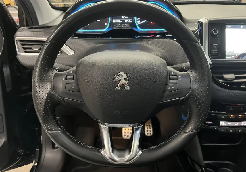 Vue rapprochée du volant en cuir noir du Peugeot 2008 Crossway, avec tableau de bord et écran tactile en arrière-plan.