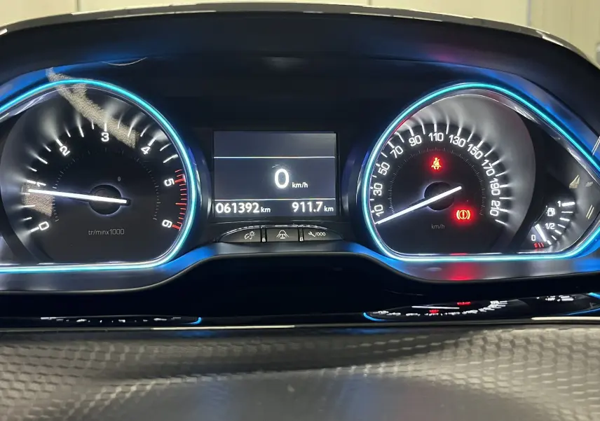 Vue rapprochée du tableau de bord du Peugeot 2008 noir, affichant le compteur de vitesse et le compte-tours éclairés en bleu.