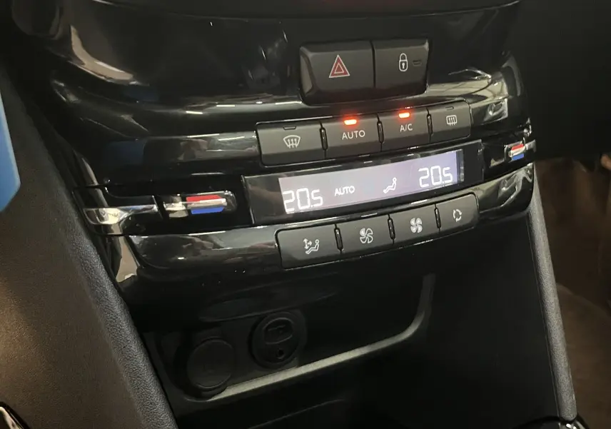 Gros plan sur la console centrale noire du Peugeot 2008, affichant la climatisation automatique réglée à 20,5°C.