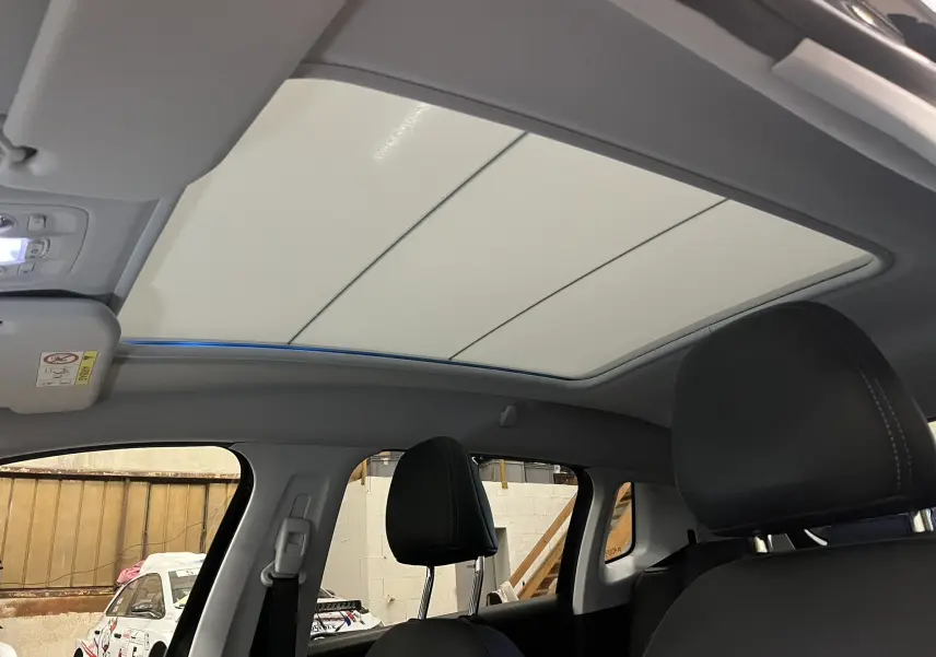 Vue intérieure du toit ouvrant panoramique fermé du Peugeot 2008 Crossway noir, avec sièges avant en cuir noir visibles.