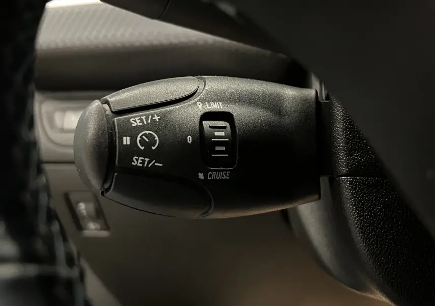 Gros plan sur la commande de régulateur de vitesse noire du Peugeot 2008 Crossway Diesel, côté gauche du volant.