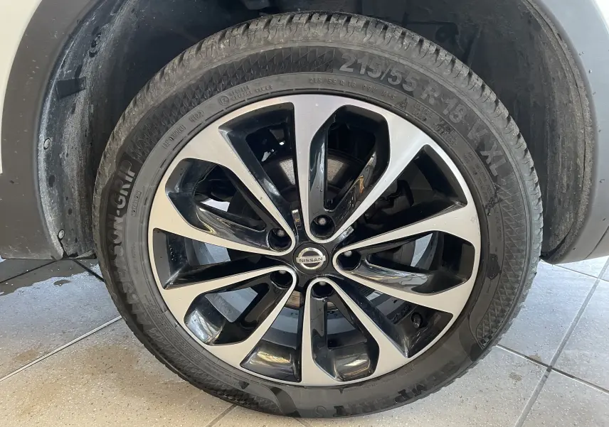 Gros plan sur la roue avant gauche du Nissan Qashqai blanc 2013, mettant en valeur la jante alliage bicolore.