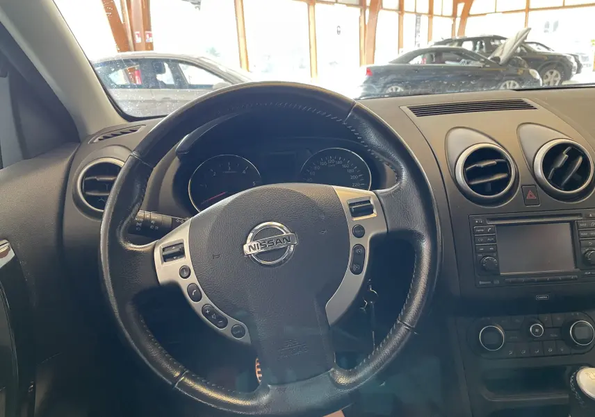 Vue intérieure centrée sur le volant noir du Nissan Qashqai 2013 avec tableau de bord et console centrale visibles.
