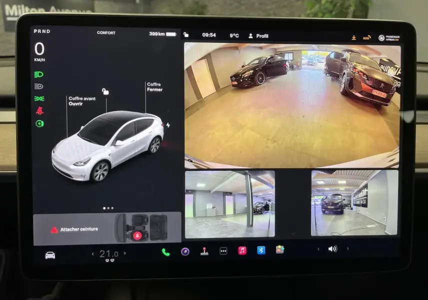 Écran tactile de Tesla Model Y blanc montrant la vue caméra 360° et l'état du véhicule en stationnement.