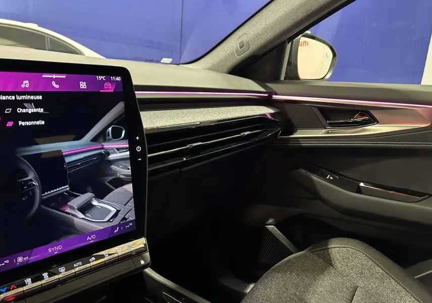 Intérieur du Renault Austral Ph.2 E-TECH noir étoilé, vue côté passager avec éclairage d'ambiance violet et écran tactile central.