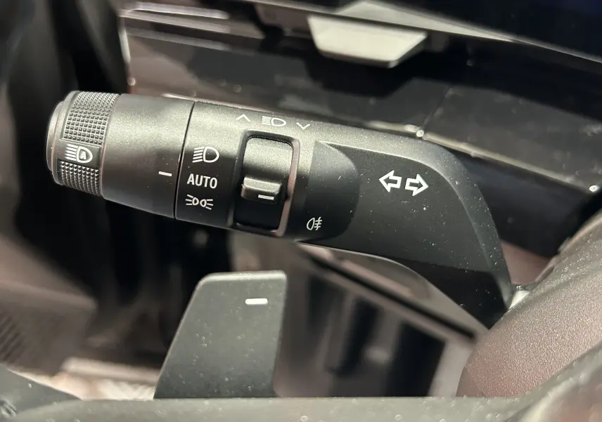 Gros plan sur la commande des clignotants et feux automatiques du volant du Renault Austral Ph.2 noir étoilé.