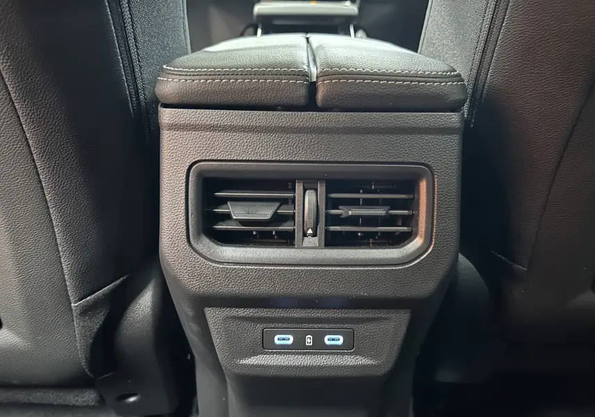 Vue rapprochée des aérateurs arrière et des ports USB bleutés sur la console centrale du Renault Austral noir étoilé 2025.