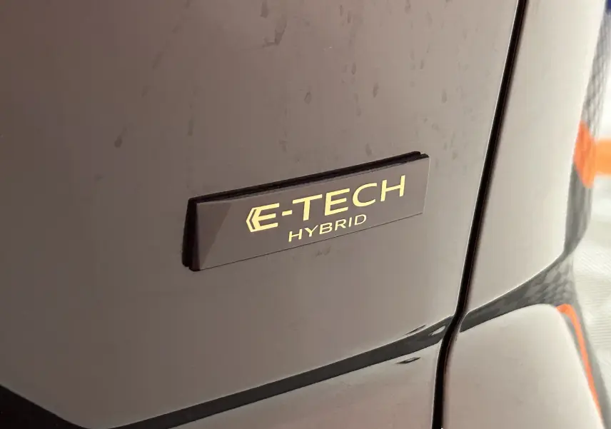 Gros plan sur l'emblème E-TECH Hybrid sur la carrosserie noire étoilée du Renault Austral Ph.2.