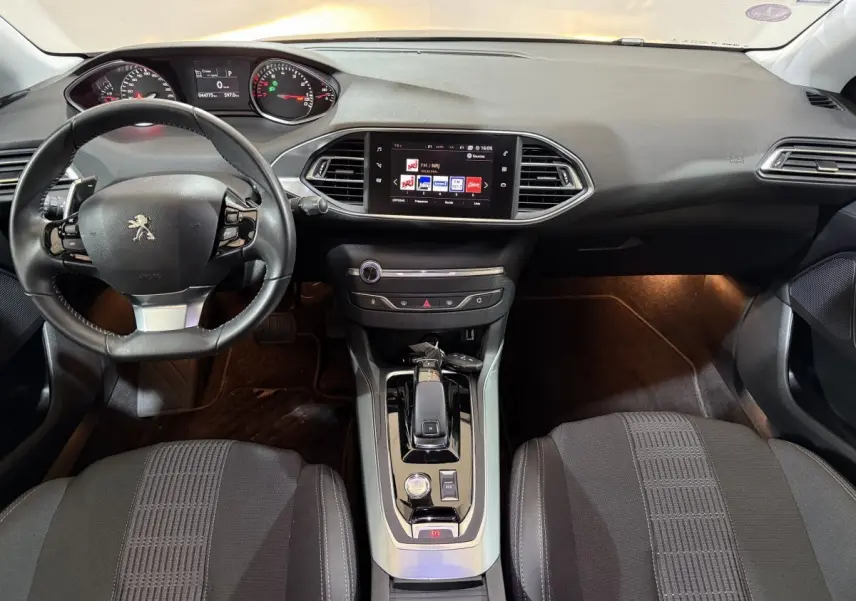 Intérieur noir de la Peugeot 308 Puretech 130, vue frontale du tableau de bord avec écran tactile et volant cuir.