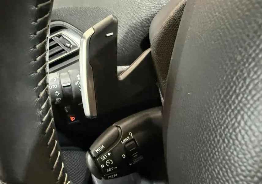 Gros plan sur les commandes de régulateur de vitesse et palettes au volant cuir noir de la Peugeot 308 2020.