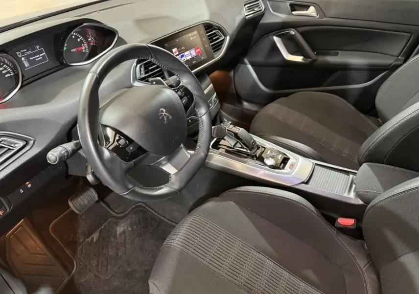 Intérieur noir de la Peugeot 308 Puretech 130 S&S EAT8 Allure, vue côté conducteur sur le tableau de bord et la console centrale.