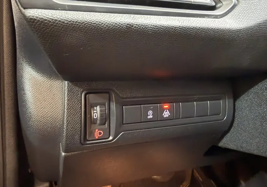 Gros plan sur les commandes d'éclairage et d'assistance au freinage côté gauche du tableau de bord d'une Peugeot 308 noire.