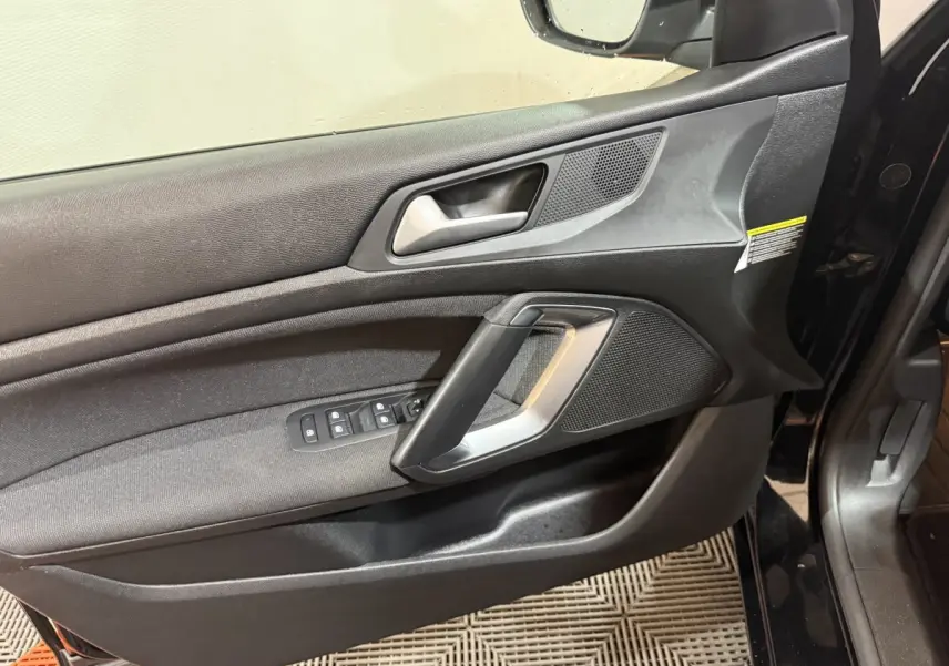 Vue rapprochée de la porte avant gauche noire du Peugeot 308 2020, avec commandes de vitres et poignée argentée.