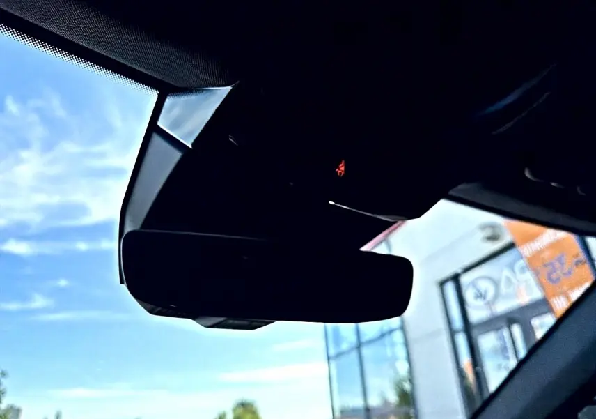 Gros plan sur le rétroviseur intérieur noir du Renault Austral 2023, avec ciel bleu visible par le pare-brise.