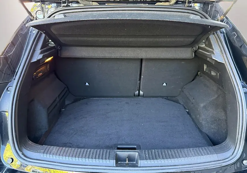 Coffre ouvert vu de l'arrière d'un Renault Austral noir, montrant un espace de chargement vide et tapis noir.