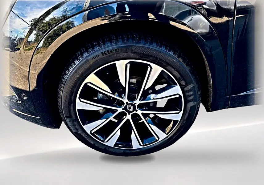 Gros plan sur la roue avant droite noire du Renault Austral 2023 avec jante alu bicolore et carrosserie noire brillante.