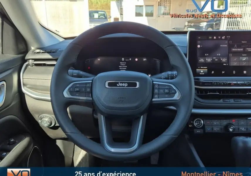 Vue frontale du volant et tableau de bord du Jeep Compass gris 2024 avec écran tactile et commandes au volant.