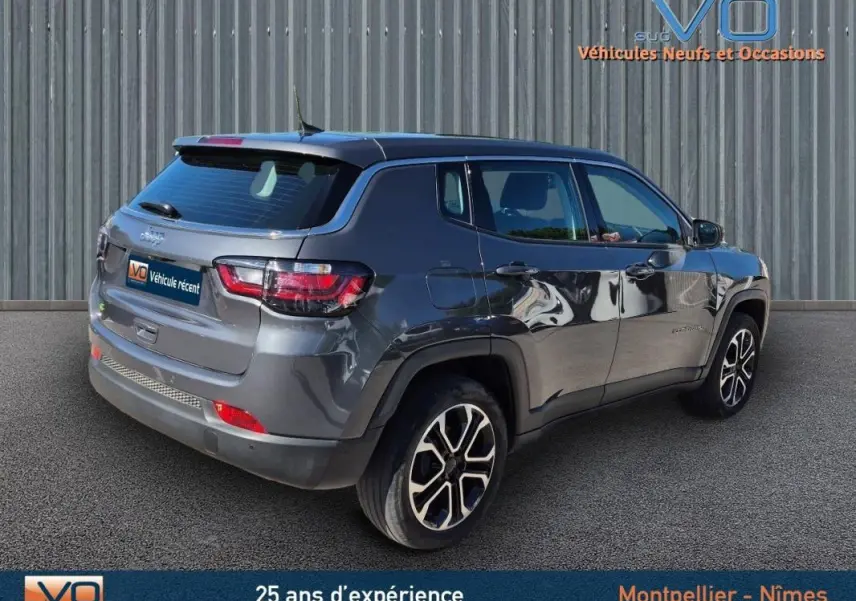 Jeep Compass gris 3/4 arrière droit, jantes alliage 18 pouces, feux LED et rétroviseurs électriques rabattables visibles.