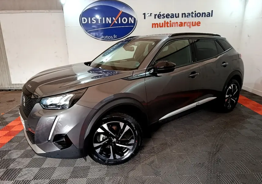 Peugeot 2008 gris foncé en 3/4 avant droit, avec jantes noires et toit noir dans un showroom intérieur.