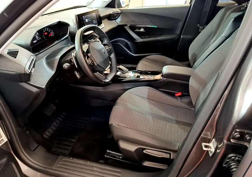 Intérieur avant droit du Peugeot 2008 gris foncé, montrant sièges tissu, volant multifonctions et tableau de bord digital.