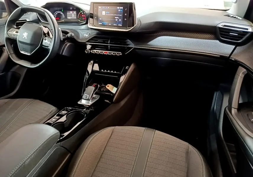 Intérieur Peugeot 2008 PureTech 130 2022 vu côté passager, tableau de bord noir avec écran tactile et volant cuir.