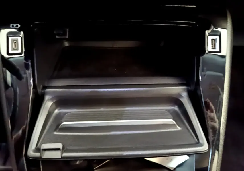 Gros plan sur la boîte à gants ouverte avec ports USB visibles dans l’habitacle noir du Peugeot 2008 gris foncé.