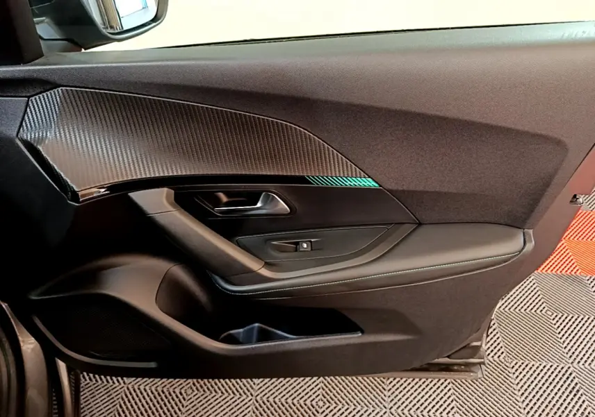 Vue côté gauche de la porte intérieure noire avec insert effet carbone du Peugeot 2008 gris foncé 2022 PureTech Allure.