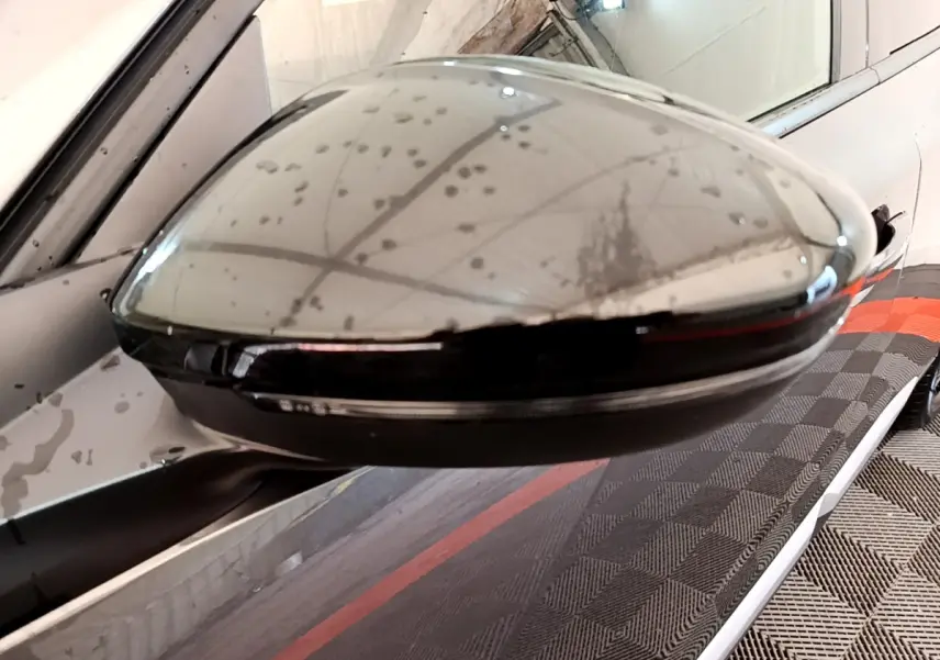 Rétroviseur droit gris foncé du Peugeot 2008 PureTech 130 en gros plan avec reflet du plafond et carrosserie visible.