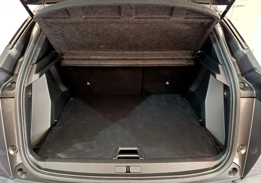 Coffre ouvert vu de l'arrière d'un Peugeot 2008 gris foncé avec plancher plat et tablette de séparation relevée.