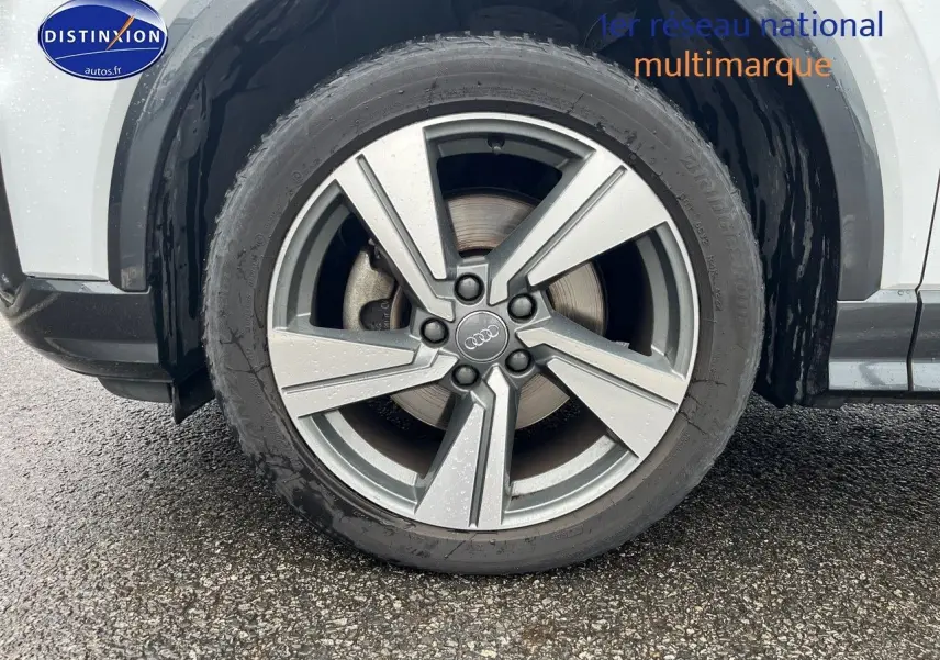 Gros plan sur la jante alu 18 pouces style 5 branches du côté avant droit d’un Audi Q2 blanc Ibis.