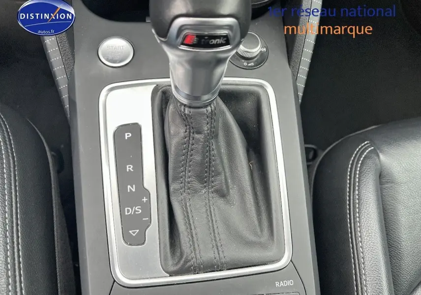 Gros plan sur la console centrale d'Audi Q2 avec levier de vitesses S tronic en cuir noir et accoudoir latéral.