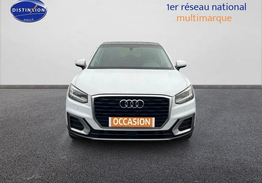 Vue frontale d'un Audi Q2 blanc Ibis avec calandre noire et plaque "OCCASION" orange visible.