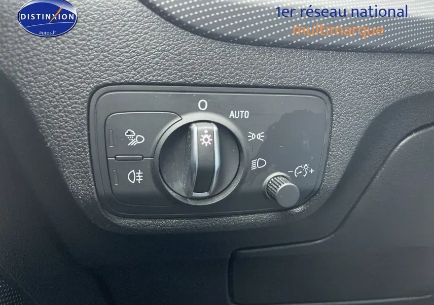 Gros plan sur le bouton de commande des phares dans l’habitacle de l’Audi Q2 blanc Ibis, côté gauche.
