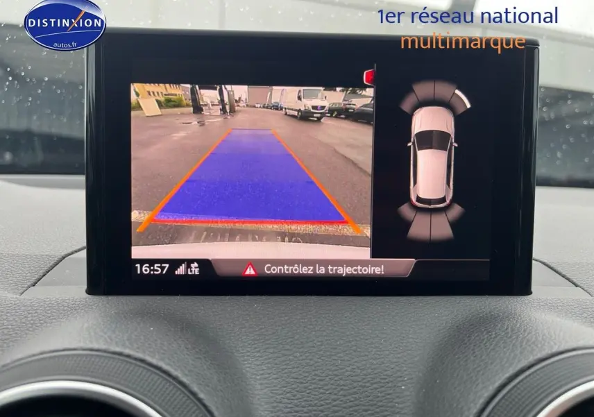 Écran intérieur affichant la caméra de recul et le système de parking sur Audi Q2 blanc Ibis, vue de face du tableau de bord.