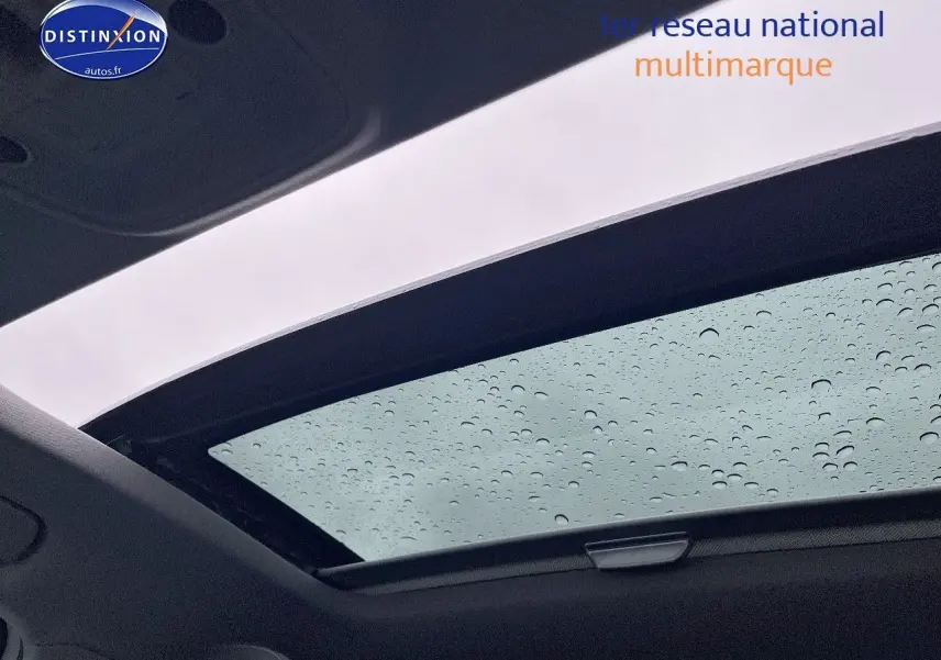 Toit ouvrant électrique coulissant d'un Audi Q2 blanc Ibis vu de l'intérieur avec gouttes de pluie visibles sur la vitre.