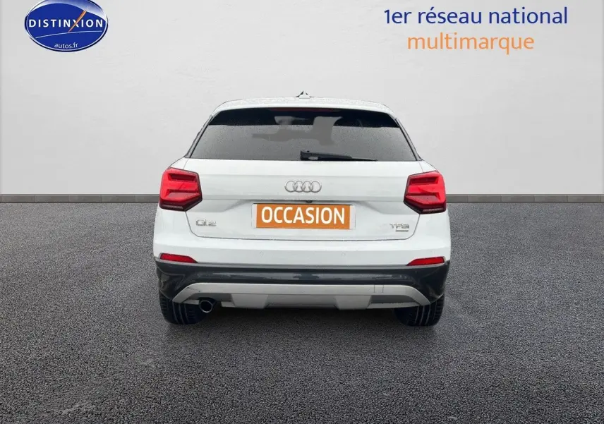 Vue arrière d'un Audi Q2 blanc Ibis de 2018 avec feux rouges et plaque "OCCASION" visible sur fond neutre.