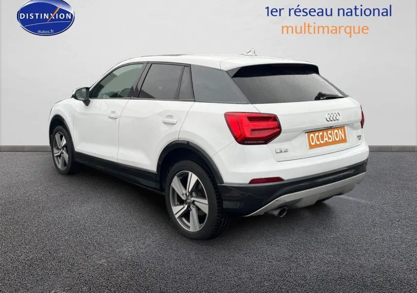 Audi Q2 blanc Ibis en 3/4 arrière droit avec jantes alu 18 pouces et vitres surteintées.