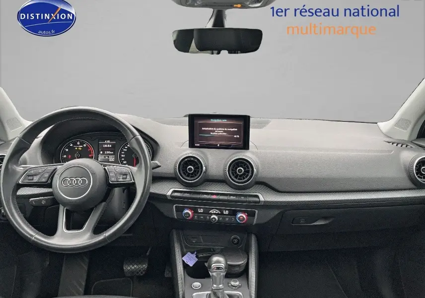 Vue intérieure avant de l'Audi Q2 2018 avec tableau de bord noir, volant cuir multifonction et écran central intégré.